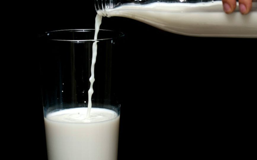 person pouring milk in highball glass