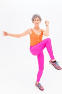 woman in purple tank top and pink leggings doing aerobics to prevent heart attack problems