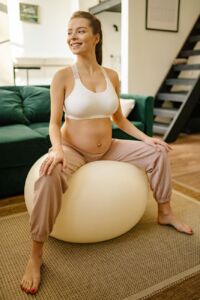 Smiling woman sitting on a birthing ball during the first stage of labor