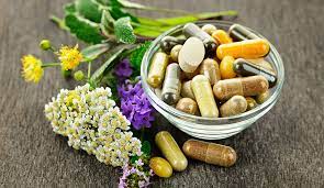 Variety of herbs complementing a bowl of capsules for well-being.