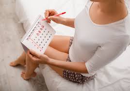 Woman circling dates on a calendar for menstruation cycle tracking