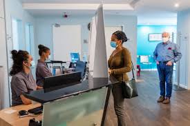 Person wearing a facemask while standing at the receptionist desk in the emergency room requiring admission or discharge from the institution