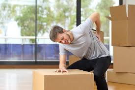 Man sitting on box, leaning forward, experiencing lower back pain