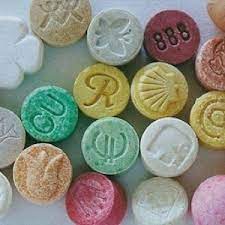 Assorted colored ecstasy tablets on a counter top