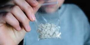 Person holding a sachet of methamphetamine: substance abuse