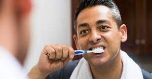 Man maintaining Dental Hygiene by brushing teeth, reflecting in a mirror - Essential daily routine for a healthy smile.