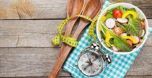 Clock beside a plate of nutritious meal on the countertop, highlighting the significance of eating on time for overall health and well-being.