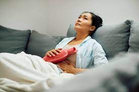 Woman experiencing endometriosis pain finds relief with a warm bottle on her abdomen – a visual representation of the challenges and coping strategies associated with endometriosis.