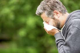 Person demonstrating proper cough etiquette, sneezing into a tissue.