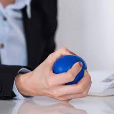 Person finding serenity with a meditation session, gently squeezing a stress ball for relaxation and stress relief.