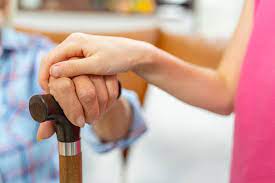 Parkinson's disorder support: A compassionate person rests their hand on the hand of someone holding a cane.