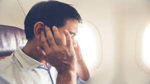 Person seated in airplane holding ears - Air Pressure Discomfort