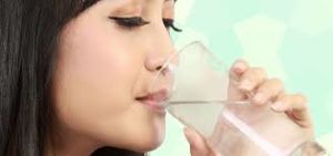 Woman hydrating with water to alleviate dry mouth