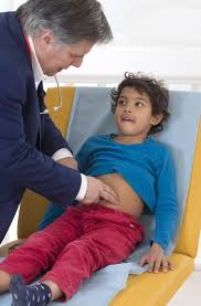 Doctor palpating child's abdomen during examination for IBS diagnosis