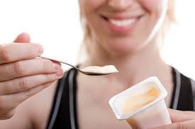 Woman smiling while holding up a spoonful of delicious yogurt