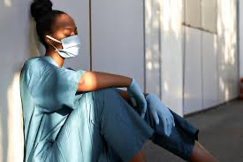 Healthcare worker sitting on floor resting against the wall