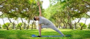 Man practicing yoga in the park. Find serenity to mentally refresh through outdoor yoga sessions amid nature's tranquility.