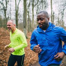 Two men jogging in the park, promoting physical activity to mitigate men's health risks 