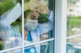 Exhausted healthcare worker facing mental health challenges, resting against the window