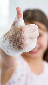 Child with soapy hands making a thumbs-up sign