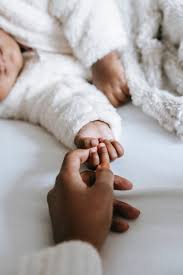 Mother holding the hand of a peacefully sleeping baby, exemplifying the comforting touch and warmth essential for a secure and restful slumber.