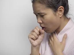 Woman coughing while holding her hand over her mouth due to the common cold