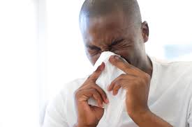 man sneezing into a tissue to prevent the spread of germs