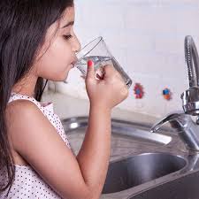 Child enjoying a refreshing glass of water, promoting the importance of staying hydrated for overall well-being.