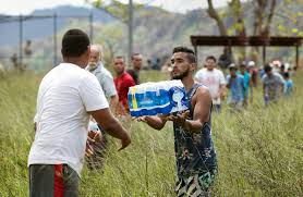 Handing out cases of water to persons during disaster relief efforts