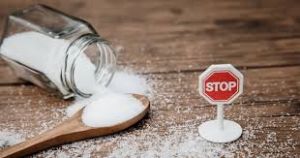 An image capturing a jar of spilled sugar on a kitchen surface, with a spoonful and a stop sign, symbolizing the need for caution and moderation in sugar consumption.