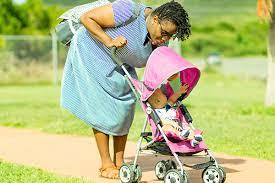 Woman outdoors bonding with her baby in a stroller after receiving Maternity Grant.