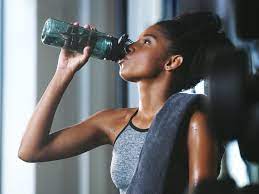 Post-exercise hydration: Woman replenishing with a water bottle, underscoring the importance of staying hydrated after a workout for optimal recovery.