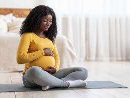 Pregnant woman sitting on the floor bonding with her baby during maternity leave