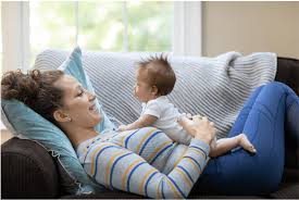 Woman laying on the sofa with her baby on her stomach, enjoying precious bonding moments during maternity leave