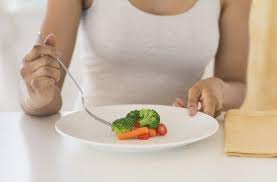 Woman enjoying a small portion from a large plate, illustrating mindful eating and the importance of portion control for sustainable lifestyle changes.