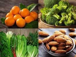 Close-up of orange slices, leafy greens, and assorted nuts - a diverse array of calcium sources.