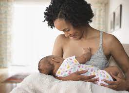 Joyful woman practicing breastfeeding with a radiant smile while bonding with her baby – a harmonious combination of motherhood and birth control choices.