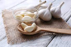 Garlic heads with spoonful of loose garlic on countertop