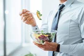 Man enjoying a nutritious salad, showcasing a commitment to healthy nutrition and wellness.