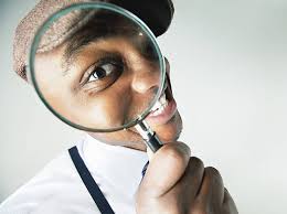 Man examining closely through a magnifying glass, emphasizing the importance of clear vision and attention to detail.