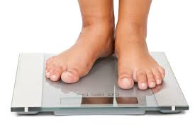 Person standing on a scale, highlighting the direct measurement of weight and its significance in addressing obesity concerns.