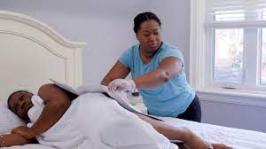 Caregiver ensuring clean bedlinen for bedridden individual