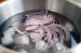 A pot of sliced onions in water, highlighting the health benefits of onions in nutrition and culinary delights.