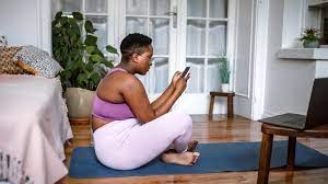 Woman seated on the floor performing a Kegel exercise, multitasking with her mobile phone.