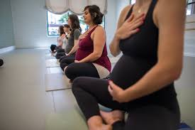 Prenatal yoga class in session with expectant mothers practicing poses.