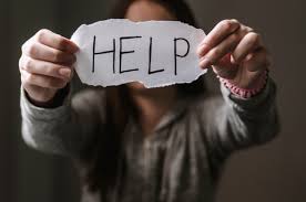 Domestic violence survivors: Image of a person holding up a paper with the word 'help,' representing reaching out for support in cases of domestic violence.