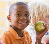 Smiling boy holding a nutritious apple, symbolizing health and happiness.