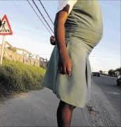 Teenage girl in school uniform standing by roadside, representing the challenges of teenage pregnancy.