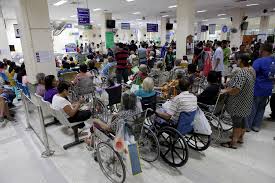 Crowded hospital lobby with persons in wheelchairs and beds 