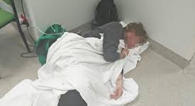 Person laying on floor due to hospital bed shortages